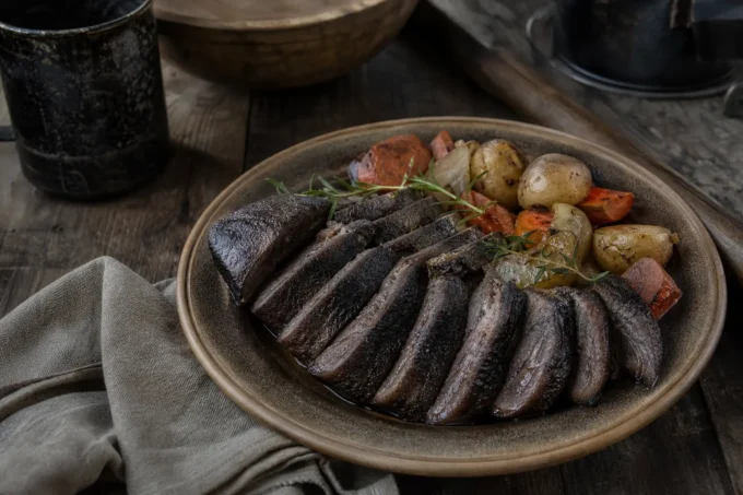 Round plate of grilled dark vegetables topped with rosemary and served with roasted mushrooms and potatoes